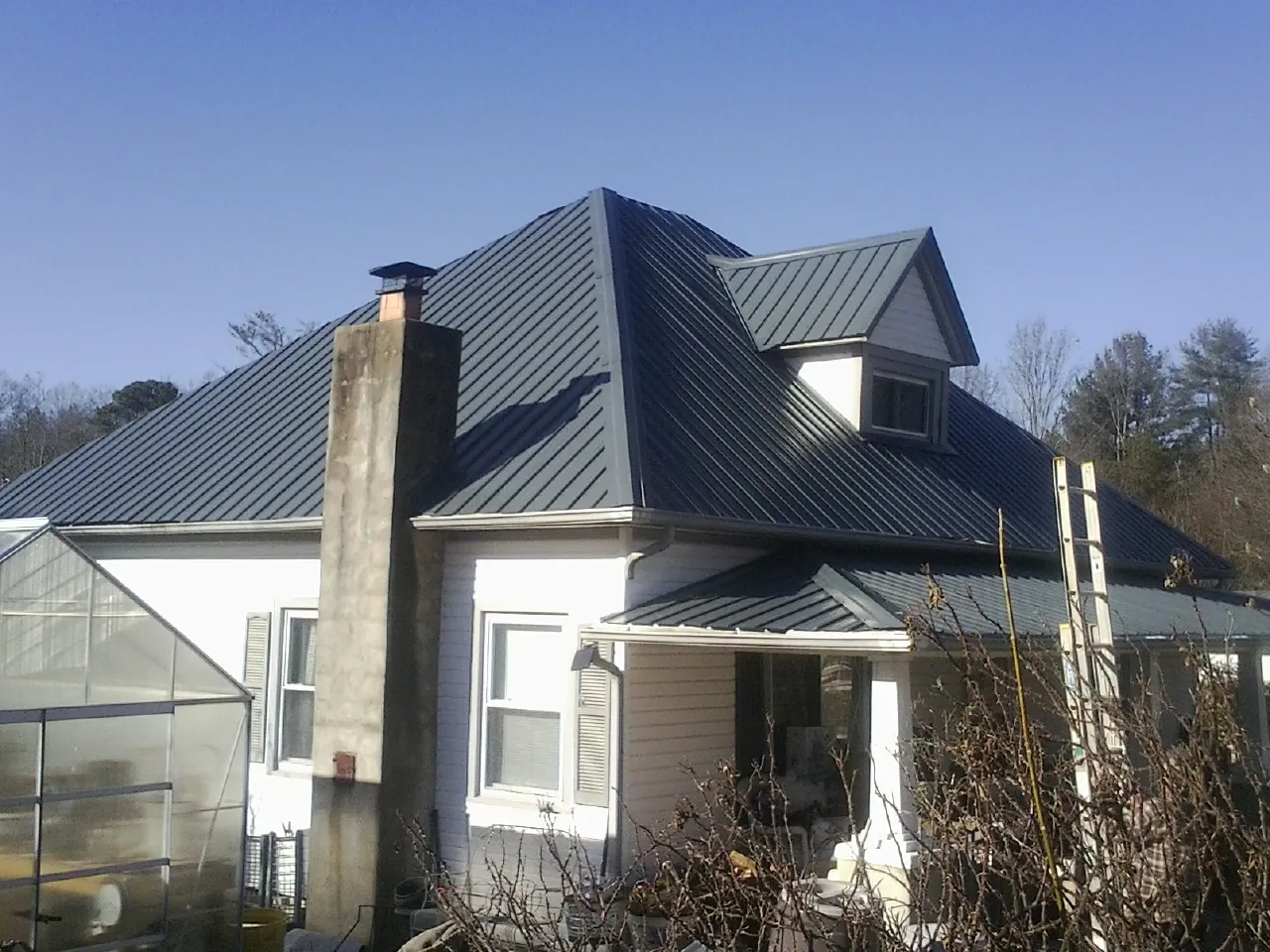 Dark blue standing seam metal roof on a white farmhouse with dormer — Slate & Tile Roof Repair by Roofing Brothers in Radcliff