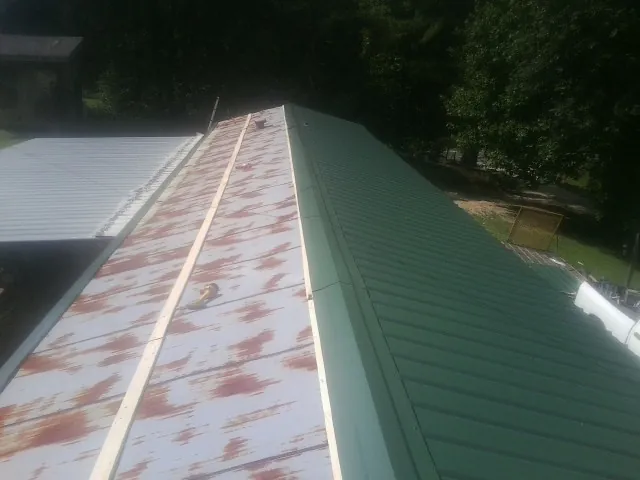 Old rusted panels beside newly installed green metal roofing — Wind Damage Roof Repair by Roofing Brothers in Radcliff