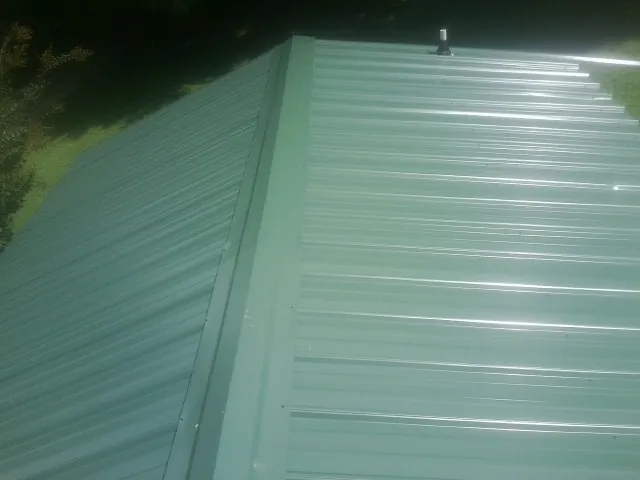New green metal panels meeting at the ridge of a roof — Flat Roof Repair work by our crew in Radcliff