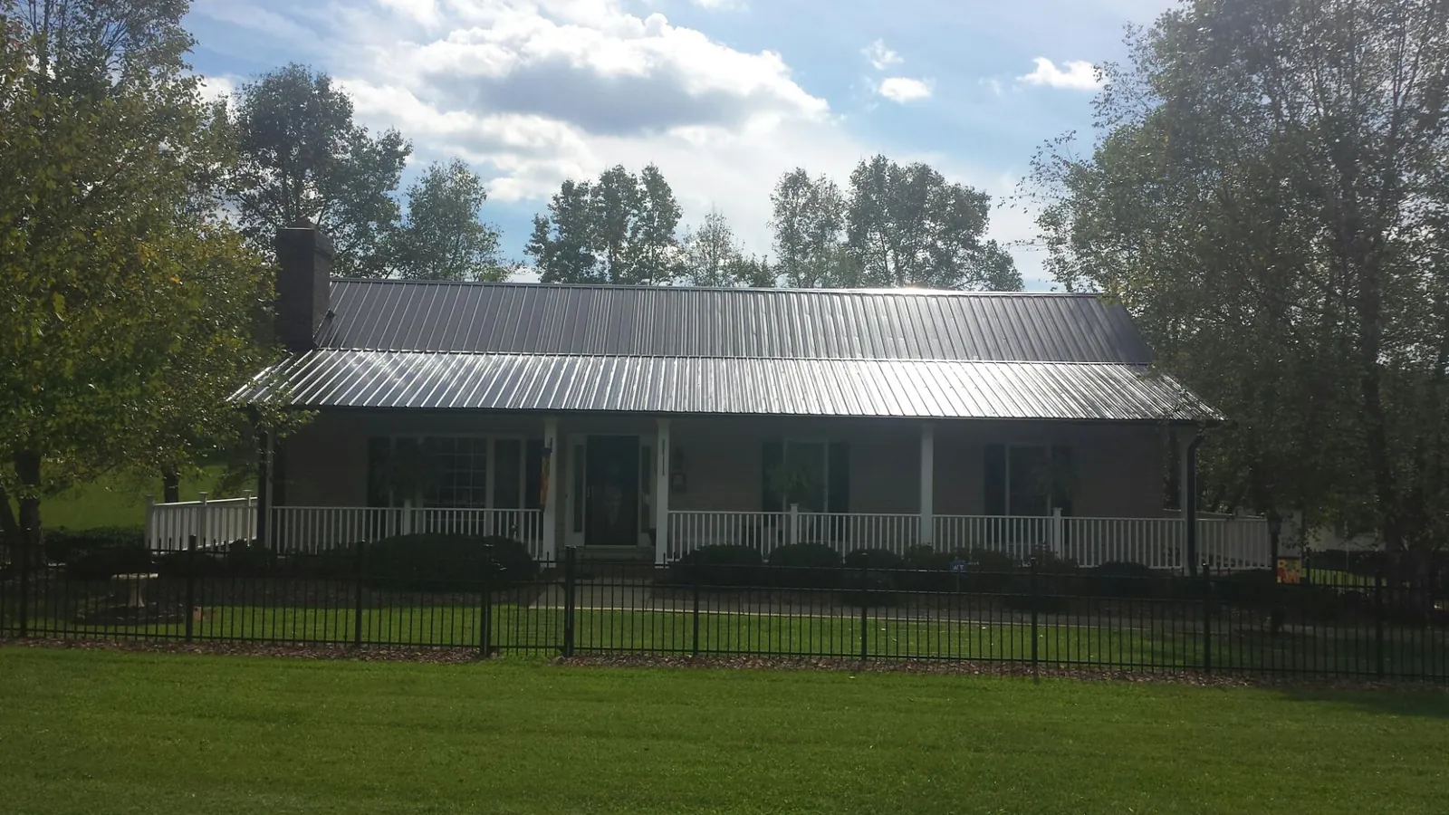 Gray metal roof on a brick ranch with a full width front porch — Gutter Guard Installation work by our crew in Radcliff