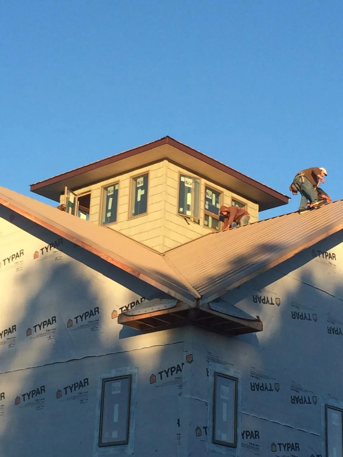 Roofers working around a rooftop cupola on a new metal roof at sunset — Roof Waterproofing in Radcliff by Roofing Brothers